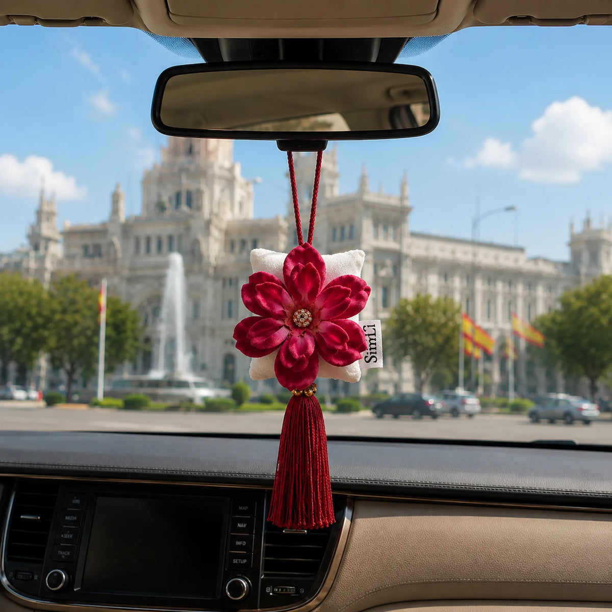 Colgante decorativo textil SimLi colgado en el espejo retrovisor de un coche con vistas a Madrid.
