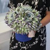 Arreglo floral artificial con rosas Jardín de Jade mostrado en las manos para apreciar su tamaño