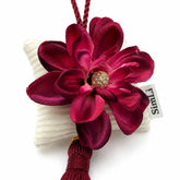 Detalle de la flor burdeos en un colgante decorativo artesanal SimLi con cojín textil y borla.