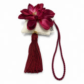 Colgante decorativo artesanal de SimLi con flor burdeos, cojín textil blanco y borla.