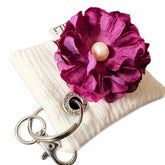 Llavero textil Ciruela con flor decorativa y detalle de perla sobre fondo blanco