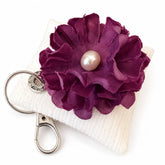 Llavero textil Ciruela con flor morada y perla sobre fondo blanco