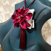 Colgante decorativo artesanal SimLi con flor burdeos sobre un busto decorativo azul, ideal para perfumar y decorar el hogar.