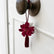 Colgante decorativo artesanal SimLi en una manilla de puerta blanca con flor burdeos y borla textil