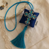 Colgante decorativo artesanal Cruz de Amalfi de SimLi Atelier sobre tejido bordado, con cruz de cristales azules y borla textil