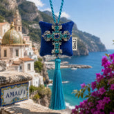 Colgante decorativo artesanal Cruz de Amalfi de SimLi Atelier con cruz de cristales azules frente a la Costa Amalfitana