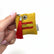 Detalle de un llavero decorativo amarillo con motivo de la bandera española en cristales y borla roja.