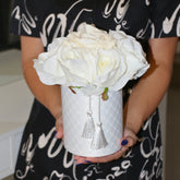 Arreglo floral de rosas blancas artificiales sostenido con ambas manos para mostrar el tamaño y las proporciones de la composición