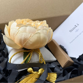 Detalle artesanal SimLi con flor textil decorativa, cojín hecho a mano y presentación de regalo preparada en el atelier