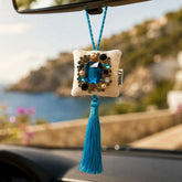 Zafiro de Ibiza colgado del espejo retrovisor de un coche, colgante decorativo artesanal de terciopelo con cristal azul y borla turquesa de SimLi Atelier.